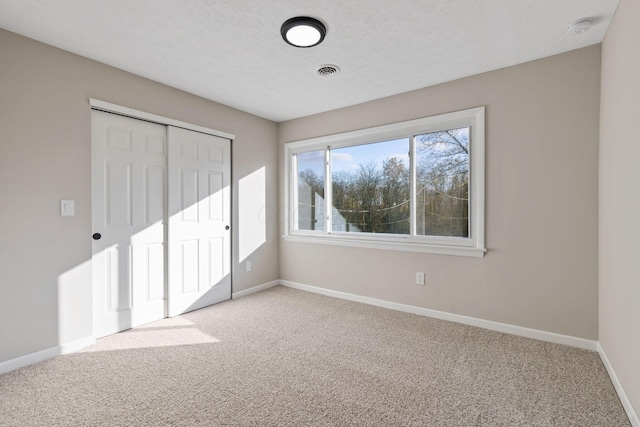 unfurnished bedroom with a closet, light carpet, and a textured ceiling