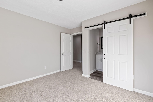 unfurnished bedroom with a barn door, carpet, and a textured ceiling