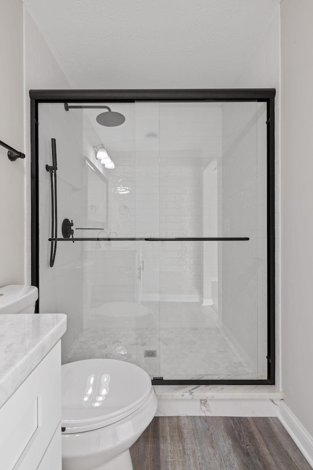 bathroom with hardwood / wood-style flooring, vanity, an enclosed shower, and toilet