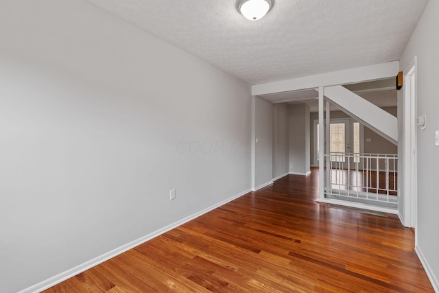 unfurnished room featuring dark wood-type flooring and a textured ceiling