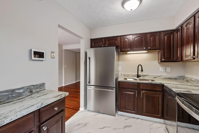 kitchen with stainless steel refrigerator, sink, dark brown cabinets, and range with electric cooktop