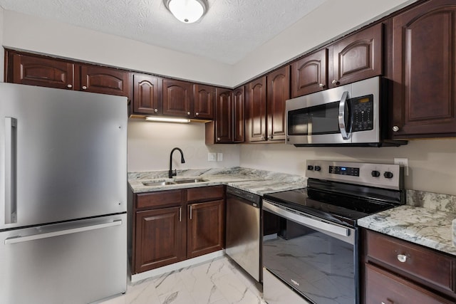 kitchen with sink, dark brown cabinets, a textured ceiling, appliances with stainless steel finishes, and light stone countertops