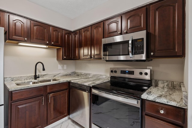 kitchen with sink, stainless steel appliances, a textured ceiling, and light stone countertops