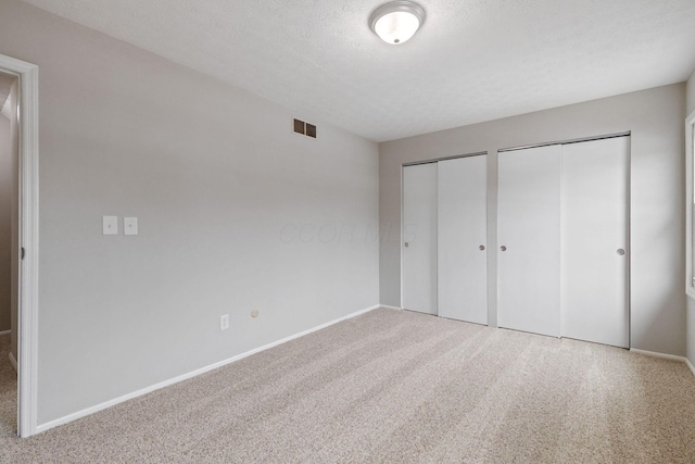 unfurnished bedroom with multiple closets, carpet flooring, and a textured ceiling