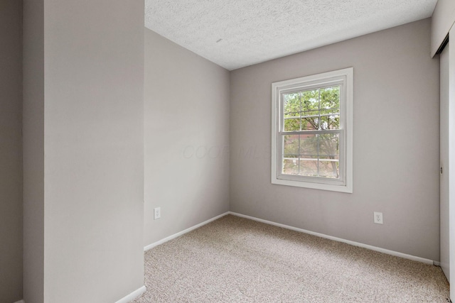 carpeted empty room featuring a textured ceiling