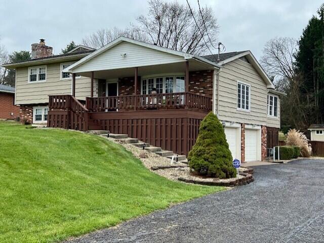 view of front facade featuring covered porch, a front yard, and a garage