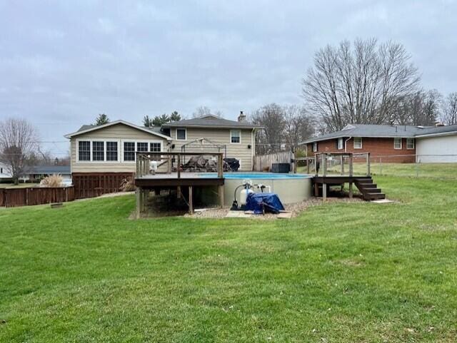 back of property with a swimming pool side deck and a yard