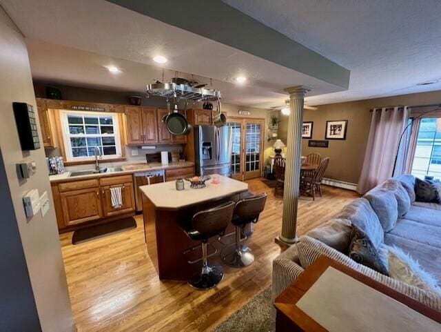 kitchen with a center island, sink, appliances with stainless steel finishes, light hardwood / wood-style floors, and decorative columns