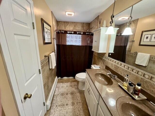 bathroom featuring tile patterned floors, vanity, baseboard heating, tile walls, and toilet