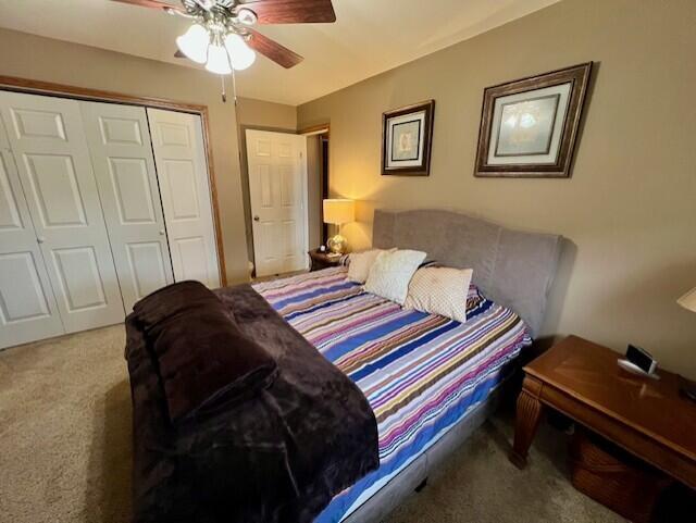 bedroom with ceiling fan, light carpet, and a closet