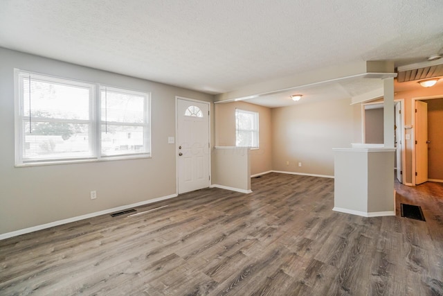 foyer entrance featuring a textured ceiling, wood finished floors, visible vents, and baseboards