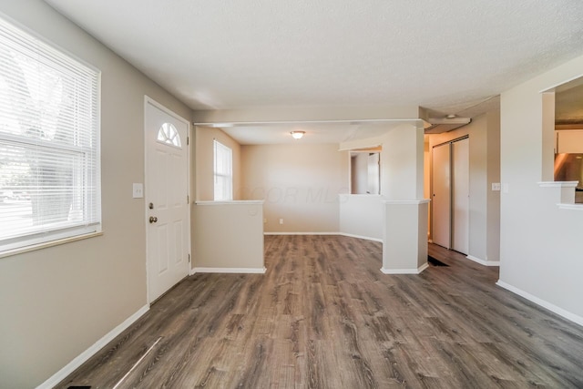 foyer entrance with a textured ceiling, wood finished floors, and baseboards