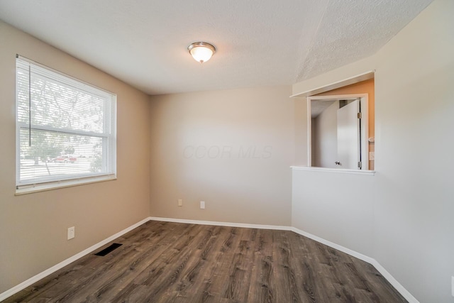 spare room featuring dark wood-style floors, visible vents, a textured ceiling, and baseboards