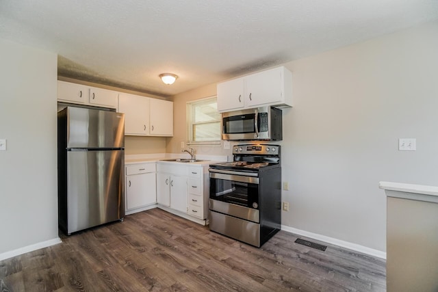 kitchen featuring stainless steel appliances, dark wood-type flooring, baseboards, white cabinets, and light countertops