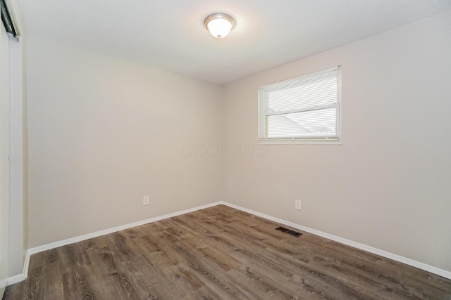 unfurnished room featuring wood finished floors, visible vents, and baseboards