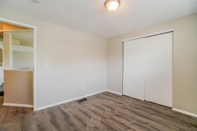 unfurnished bedroom with a closet, baseboards, and wood finished floors