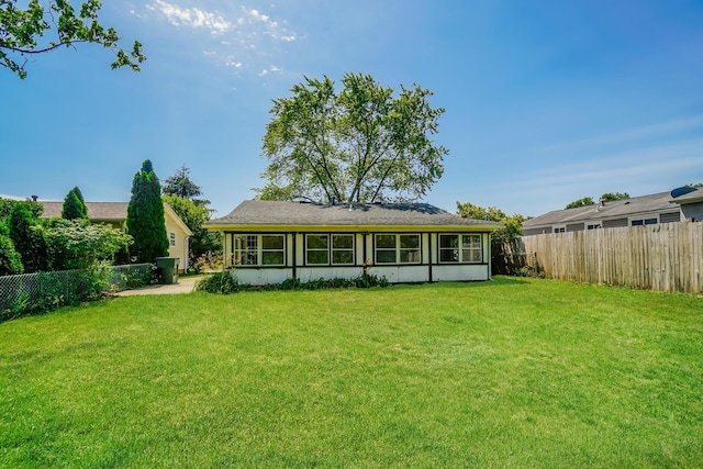 rear view of property featuring a fenced backyard and a lawn