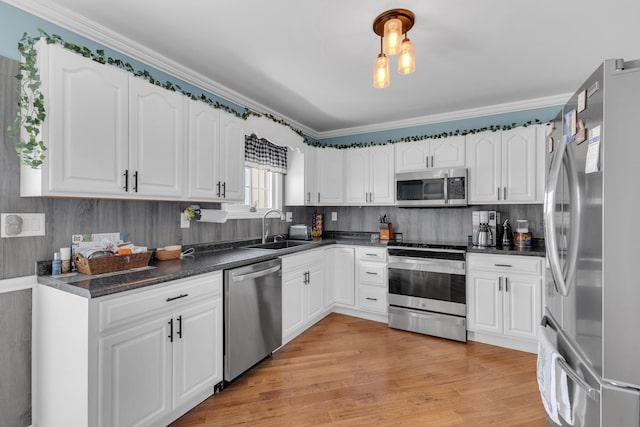 kitchen featuring dark countertops, stainless steel appliances, white cabinets, and a sink