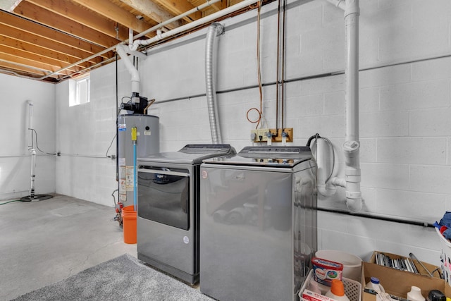 washroom featuring concrete block wall, water heater, independent washer and dryer, and laundry area
