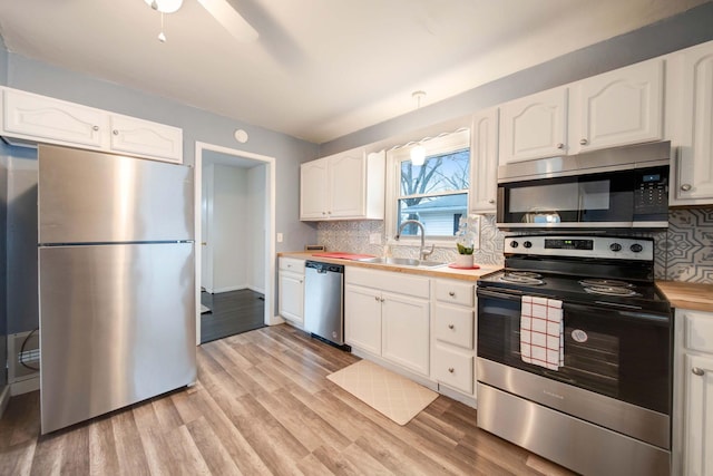 kitchen featuring light wood-type flooring, backsplash, stainless steel appliances, sink, and white cabinets