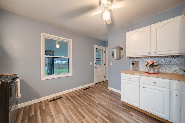 kitchen featuring light hardwood / wood-style flooring, decorative backsplash, range with electric stovetop, ceiling fan, and white cabinetry