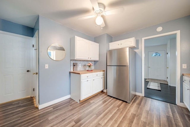 kitchen featuring decorative backsplash, stainless steel fridge, ceiling fan, light hardwood / wood-style floors, and white cabinetry