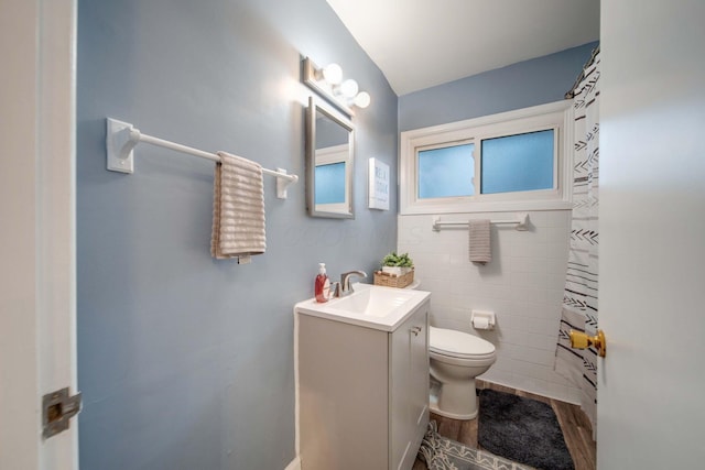 bathroom featuring hardwood / wood-style floors, vanity, toilet, and tile walls