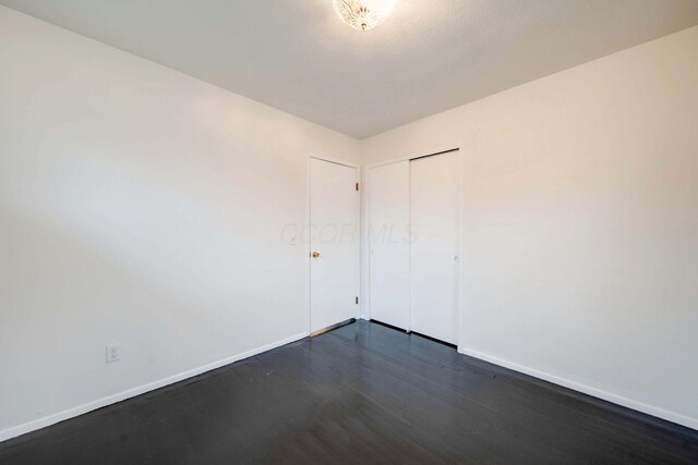 unfurnished room with dark wood-type flooring