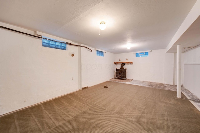 basement with a wood stove and carpet floors