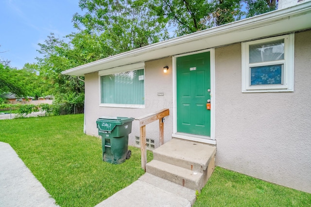 view of exterior entry with a yard