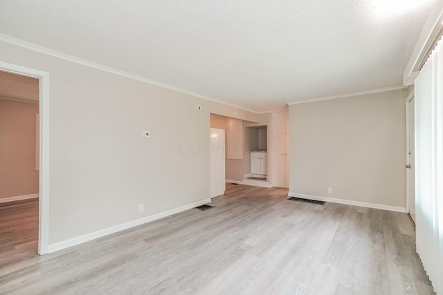 empty room with a textured ceiling, crown molding, and light hardwood / wood-style flooring