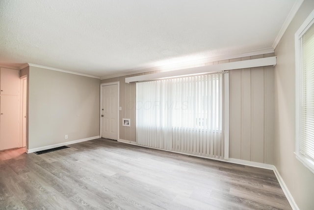 unfurnished room with hardwood / wood-style floors, a textured ceiling, and crown molding