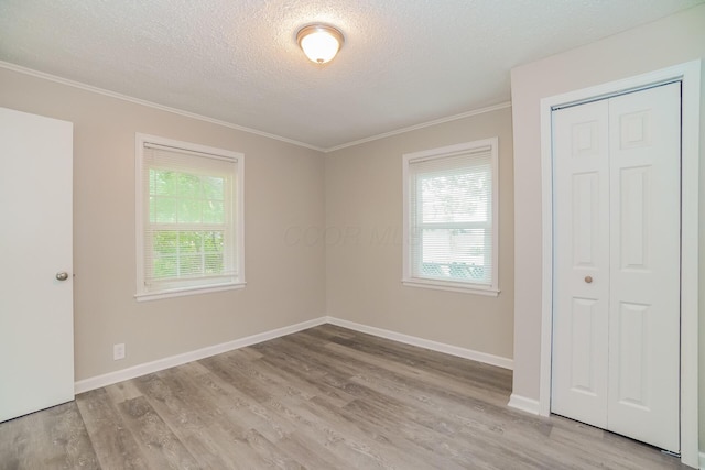 unfurnished room with light hardwood / wood-style floors, crown molding, and a textured ceiling