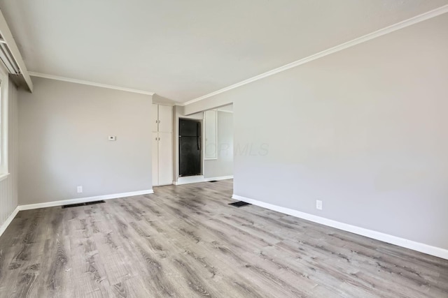 empty room with light wood-type flooring and ornamental molding