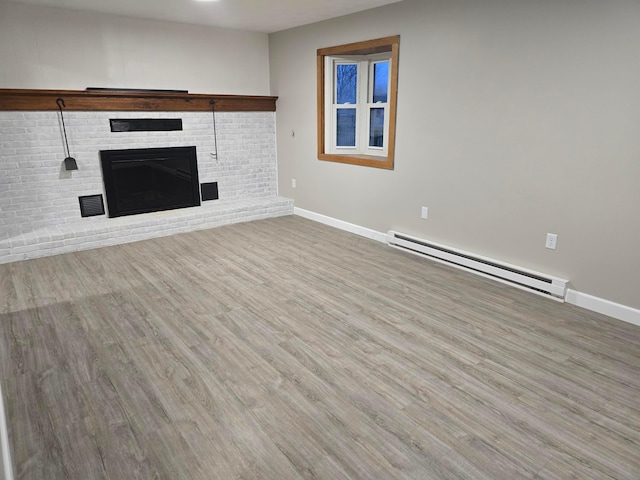 unfurnished living room with baseboard heating, hardwood / wood-style floors, and a brick fireplace