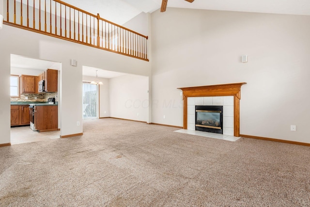 unfurnished living room featuring beam ceiling, high vaulted ceiling, a chandelier, light colored carpet, and a fireplace