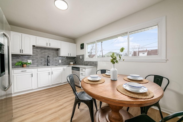 kitchen featuring tasteful backsplash, stainless steel appliances, sink, light hardwood / wood-style flooring, and white cabinets