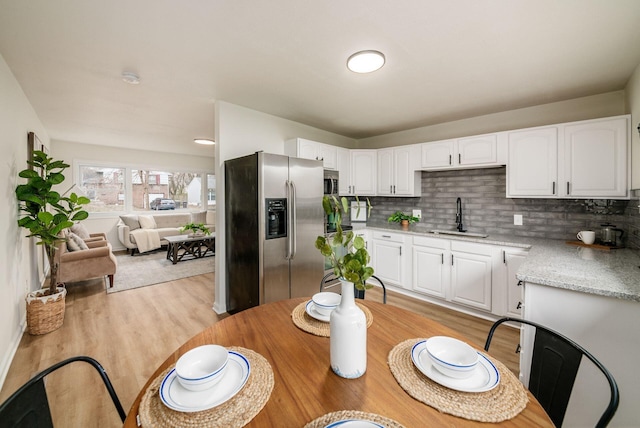 kitchen featuring tasteful backsplash, stainless steel appliances, sink, white cabinets, and light hardwood / wood-style floors