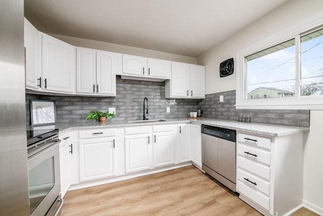 kitchen featuring decorative backsplash, white cabinets, sink, dishwasher, and light hardwood / wood-style floors