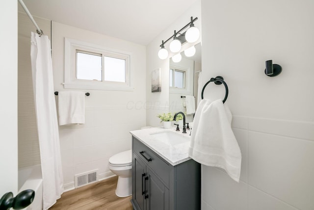 full bathroom with shower / tub combo, vanity, hardwood / wood-style flooring, tile walls, and toilet