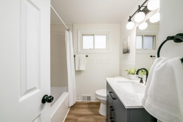 full bathroom featuring shower / bath combo, vanity, tile walls, hardwood / wood-style floors, and toilet