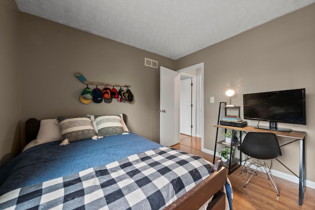 bedroom featuring a textured ceiling and light hardwood / wood-style flooring