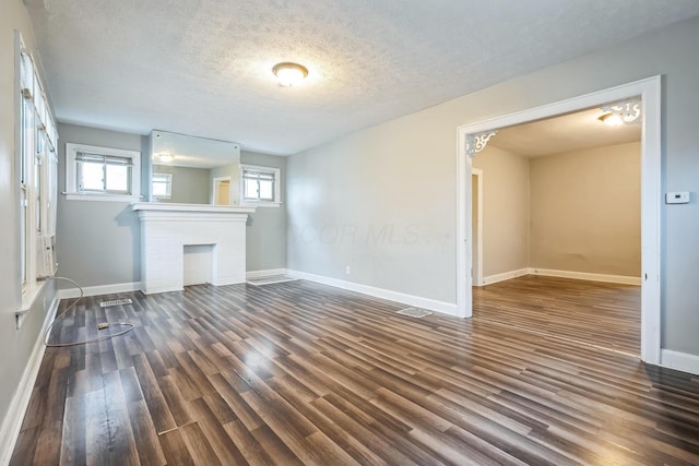 unfurnished living room with a fireplace, dark hardwood / wood-style flooring, and a textured ceiling