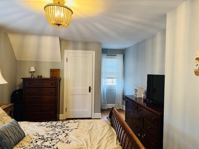 bedroom with hardwood / wood-style flooring and an inviting chandelier