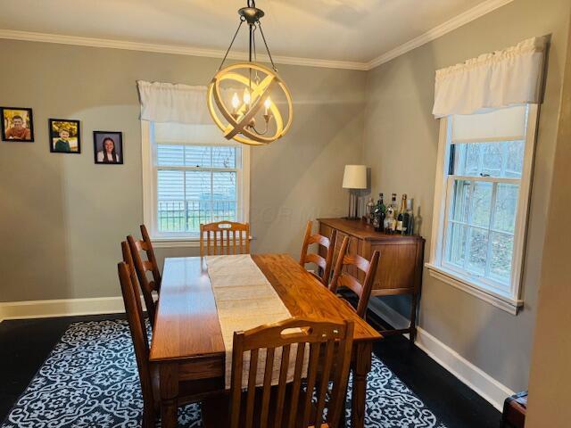 dining space featuring wood-type flooring, an inviting chandelier, and crown molding