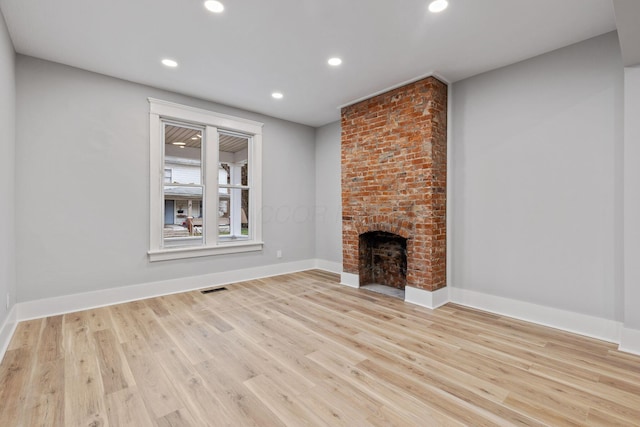 unfurnished living room featuring light hardwood / wood-style floors and a brick fireplace