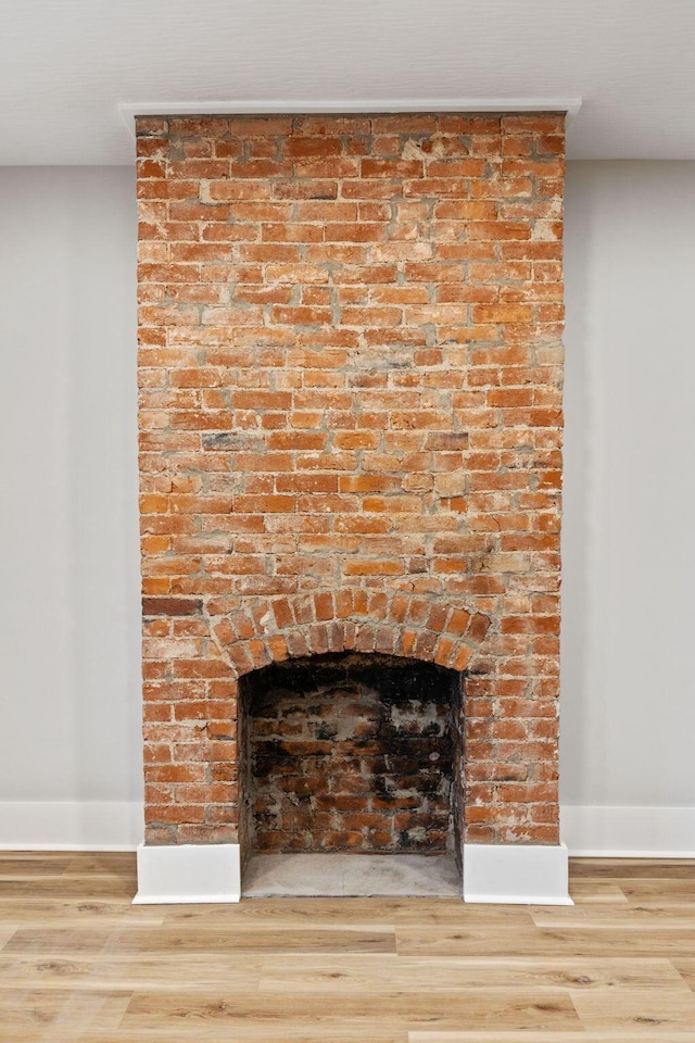 details with a brick fireplace and hardwood / wood-style flooring