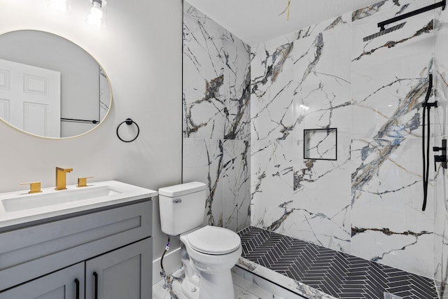 bathroom featuring toilet, vanity, and tiled shower