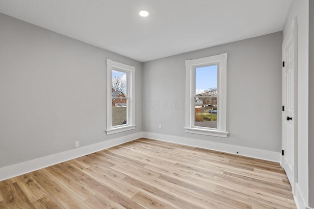 empty room with a textured ceiling and light hardwood / wood-style flooring