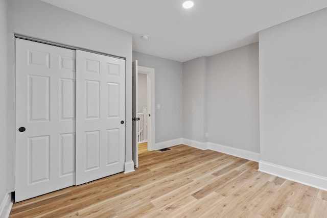 unfurnished bedroom with a closet and light hardwood / wood-style floors